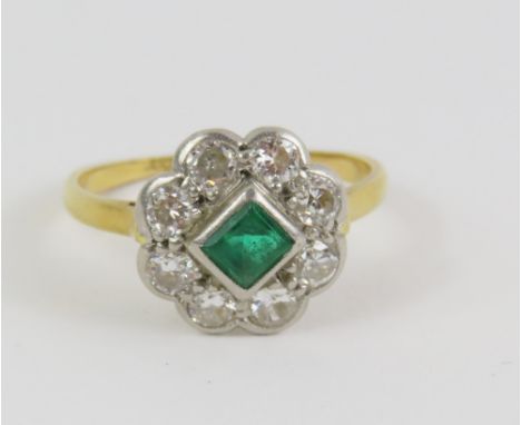An early 20th century emerald and old cut diamond cluster ring, diamond total weight approximately 0.30ct, marked '18ct', fin