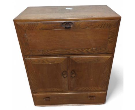 An Ercol Windsor serving cabinet, the elm wood cocktail / bureau cabinet having a drop down fronted door to top, above a twin