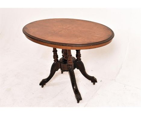 A C1880 small oval tilt top side table with quarter veneered top in walnut having inlaid scrolling leaf decoration. The base 