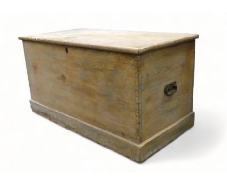 A large 19th century pine trunk - of dovetail construction, the rectangular top above steel bail handles and plinth base, wit