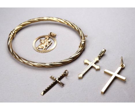 A 9ct gold bangle - of twisted oval form, together with three 9ct gold crosses and a St Christopher medal, weight 10.5g. (5)