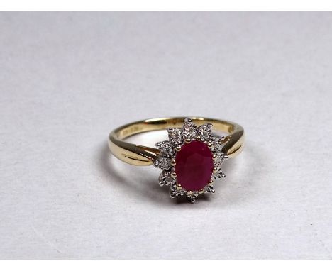 A 9ct yellow gold ruby and diamond set cluster ring - the central oval treated ruby weighing 0.92ct approximately, the diamon