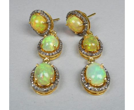 A pair of long triple halo drop opal and diamond earrings - each set with three oval cabochon opals with a halo of diamonds i