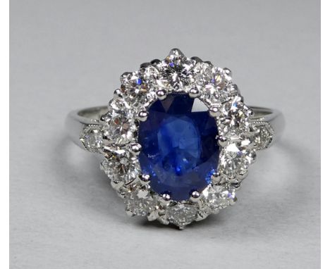 A platinum ring set a sapphire and diamonds - the central oval sapphire weighing 1.50ct approximately, surrounded by a halo o