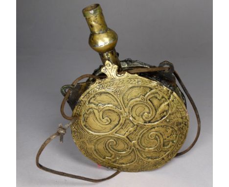 A late 19th/early 20th century Persian brass powder flask - circular with repousse decoration, of leaf form with a leather th