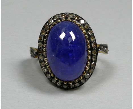 A large cabochon tanzanite and diamond set ring - with diamond shoulders, set in silver and gold, the tanzanite weighing 7.20