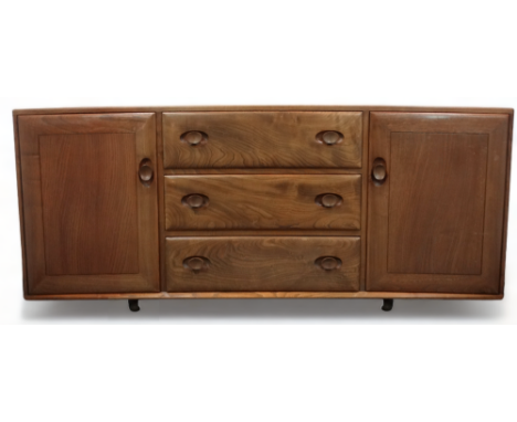 An Ercol elm sideboard - of dovetail construction, the rectangular top above three central drawers flanked by a pair of panel
