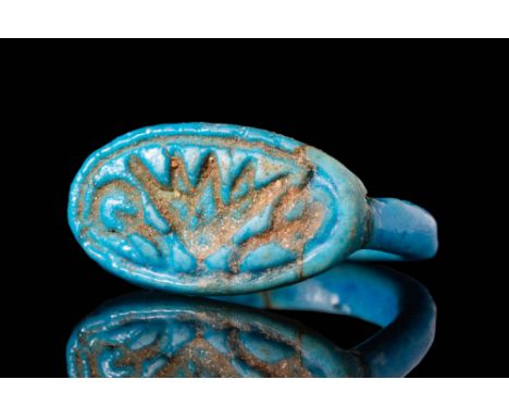 Ca. 1550 - 1070 BC An Egyptian faience ring adorned with a lotus flower on the bezel. The lustrous blue hue complements the r