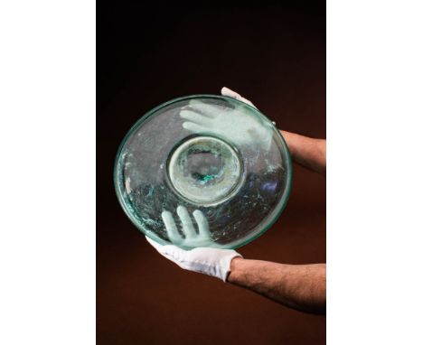 Ca. AD 300 - 400 A Roman glass dish with a circular form that is free-blown and translucent with a green hue. The dish has a 