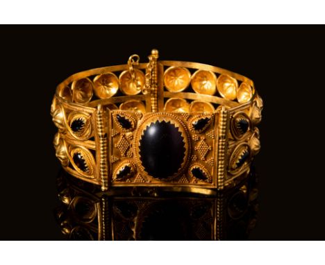 Ca. 400 - 300 BC A gold D-shaped bracelet with an intricately designed open-work body. The rounded portion of the bracelet ha