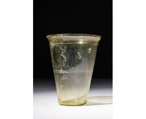 Ca. AD 100 - 300 A Roman translucent glass beaker, free-blown formed from pale yellow-hued glass. The beaker is defined by a 