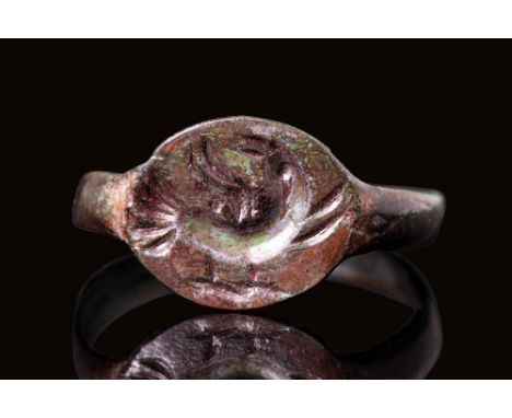 Ca. AD 700 - 1200 A Medieval bronze ring with D-shaped hoop connected to a circular bezel. The bezel depicts the Holy Dove de