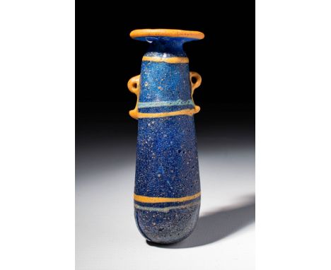 Ca. 600 - 400 BC A translucent light blue glass unguentarium, with opaque yellow handles and rim-disk. The vessel is decorate