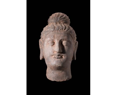 Ca. AD 200 - 400 A schist stone head of Buddha with naturalistic features. These features include deep-set almond-shaped eyes