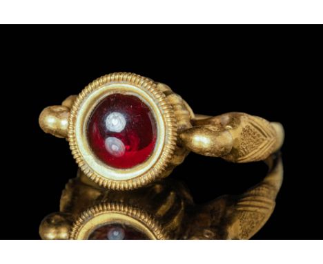 Ca. AD 500 - 600 A Byzantine gold ring with a garnet cabochon. The hoop is thick and circular with terminals in the form of s