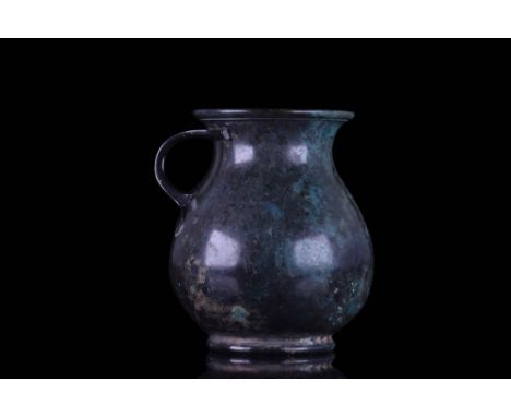 Ca. AD 100 - 300 A bronze olpe rising from a ring foot. The vessel features a globular lower body tapering to a gracefully-sh