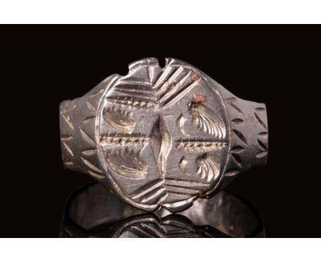 Ca. AD 900 - 1200 A medieval silver ring featuring a round bezel adorned with four stylised angels. They are in profile and d