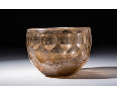 Ca. AD 200 - 600 A Sassanian mould-made pale yellow glass cup with a thick-walled hemispheric body and meticulously spaced ci