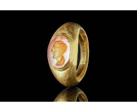 Ca. AD 100 - 300 A D-shaped gold finger ring composed of a slender hoop with large shoulders and a bezel with an intaglio. Th
