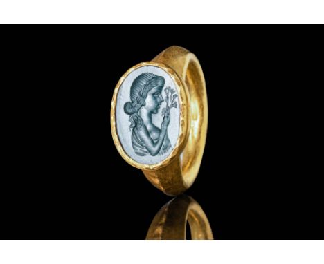 Ca. AD 300 A large Roman gold ring with a round hoop enlarged on the shoulders to form a large oval bezel. The bezel secures 