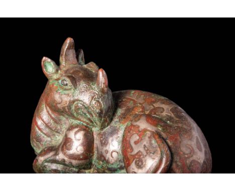 Ca. 200 - 100 BC A Han Dynasty silver-inlaid copper guardian dragon is shown reclining on its side. Moulded and decorated wit