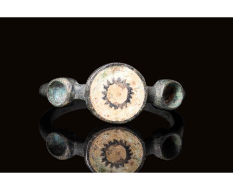 Ca. AD 200 - 400 A late Roman bronze ring with a circular bezel inlaid with an enamel depiction of the sun. The shoulder has 
