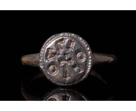 Ca. AD 900 - 1300 A medieval religius bronze signer ring featuring a round hoop connected to a circular bezel. The bezel is a