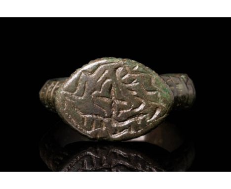 Ca. AD 900 - 1200 A Byzantine bronze ring with an almond-shaped bezel, engraved with a simplified holy cross and geometric sh