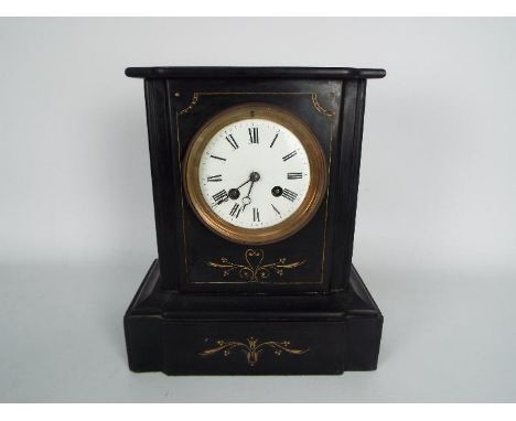 A French black slate mantel clock with incised gilt highlights, Roman numerals to a 4" enamel dial, approximately 27 cm (h).