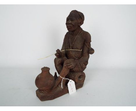 Ethnographica - An African pottery figurine, probably Kenyan, depicting a seated man dressed in a robe, incised mark to the b