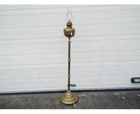 A floor standing, telescopic, brass oil lamp, approximately 144 cm (h) when at lowest setting.