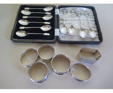 A cased set of six silver teaspoons, together with six napkin rings of different designs and four silver teaspoons with crest