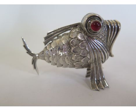 A Spanish silver pepperette in the form of an articulated model of a fish, hallmarked for 915 silver with red cabachon glass 