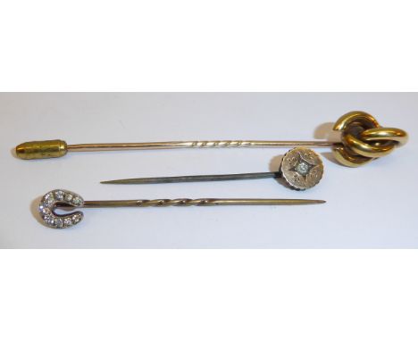 A Stick Pin of horse shoe design set with nine diamonds and two other stick pins. 