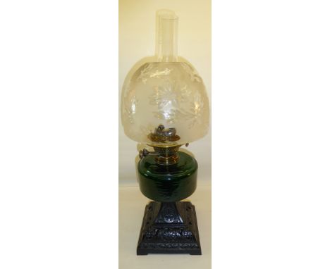 A late Victorian Oil Lamp with cast iron base, green glass reservoir and duplex twin burner with an etched glass shade. 