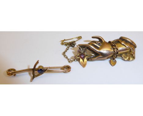 A 9ct gold Brooch in the form of a hand holding a flower set with a ruby, and gold wishbone Brooch.