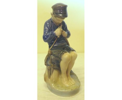 A Royal Copenhagen Figure of a boy seated on a rock whittling a stick, no. 905, 7" (18cms) high.