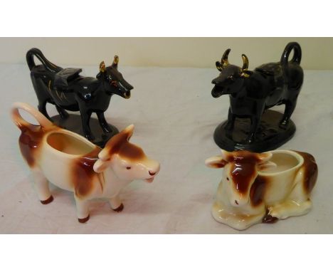 A Jackfield type pottery Cow Creamer decorated in black and gilt and two Goebel cattle ornaments.  