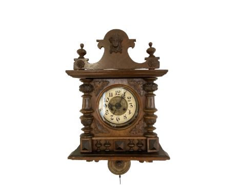 German - Edwardian 8-day striking wall clock in an oak case, with a shaped pediment, turned columns and finials, two part dia
