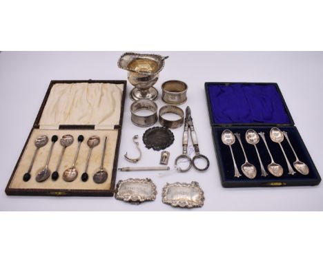 Two cased sets of silver coffee spoons; together with three silver napkin rings; two silver decanter labels; a silver swizzle