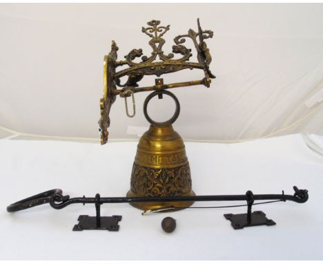 A wall mounted brass bell with scroll chased bracket and ring pull
