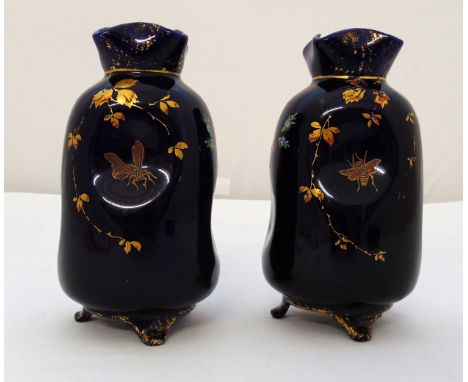 A pair of blue ground ceramic vases decorated with bees, flowers and leaves on three bracket feet, 18cm (h)