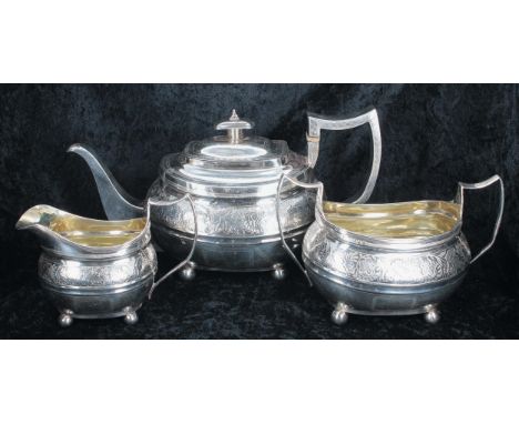 George III three piece boat shaped silver tea set, comprising teapot 6" high, twin-handled sucrier and jug, each with engrave