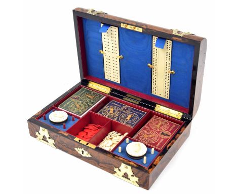 Good Victorian walnut games box, the domed cover with brass strapwork, enclosing fitted interior with playing cards and Beziq