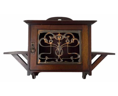 Art Nouveau mahogany wall cabinet, the panelled door with stylised pierced brass grille, flanked by two brackets, bearing pla