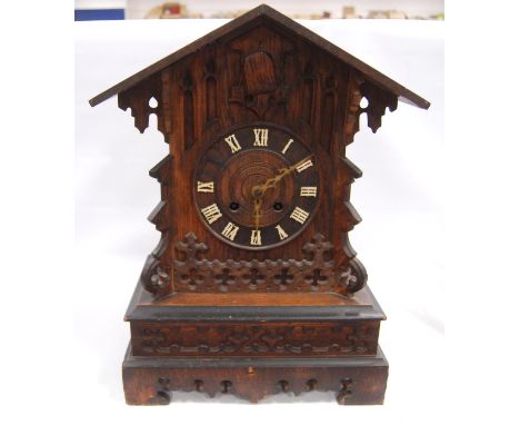 Black Forest cuckoo clock with fretwork pediment over turned face, Roman numerals, flanked by carved bracket, plinth base, br