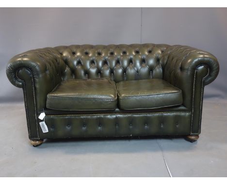 A two seater Chesterfield sofa, with green leather stud bound button back upholstery, on bun feet and castors, H.74 W.162 D.9