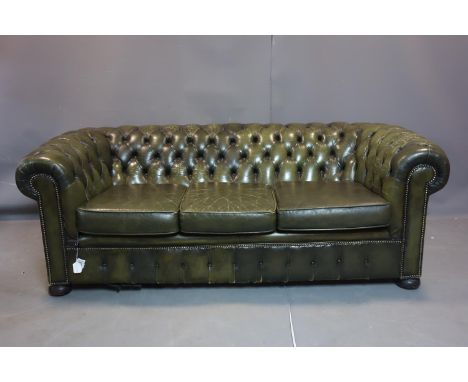 A three seater Chesterfield sofa, with green leather stud bound button back upholstery, on bun feet and castors, H.74 W.195 D