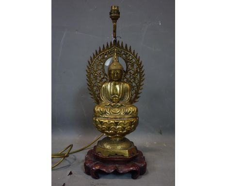 An early 20th century Chinese heavy brass statue of a seated Buddha on hardwood stand, later added with brass lamp, H.42cm 