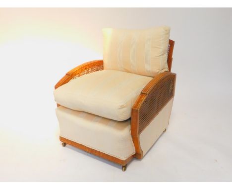 A French Art Deco faux walnut and cane armchair, with a striped fabric seat and loose cushions, 62cm wide.